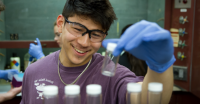 Student wearing safety glasses holding a vial in a laboratory.