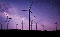 The sky is purple and dark outlines of wind turbines